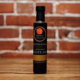 Blood Orange Infused Olive Oil bottle against a rustic brick backdrop.