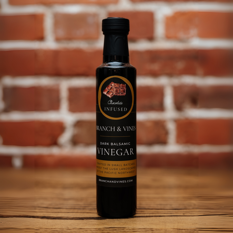 A bottle of Chocolate Dark Balsamic Vinegar displayed against a rustic brick background, offering a warm and artisanal aesthetic.