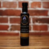 Huckleberry Dark Balsamic Vinegar bottle against a rustic brick backdrop.