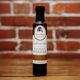 Huckleberry White Balsamic Vinegar bottle against a rustic brick backdrop.