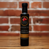 Raspberry Dark Balsamic Vinegar bottle against a rustic brick backdrop.