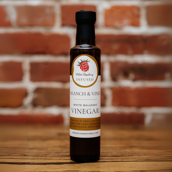 Raspberry White Balsamic Vinegar bottle against a rustic brick backdrop.