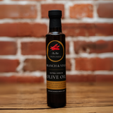 Thai Bird Chili Infused Olive Oil bottle against a rustic brick backdrop.